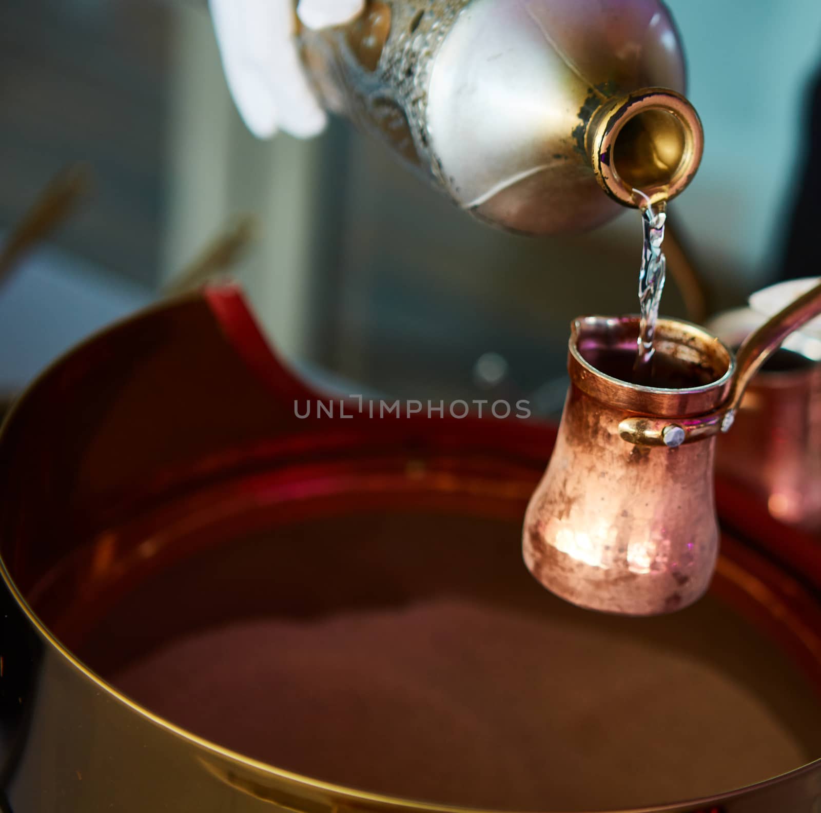 Preparation of Turkish coffee in the cezve in the sand at the cafe bar