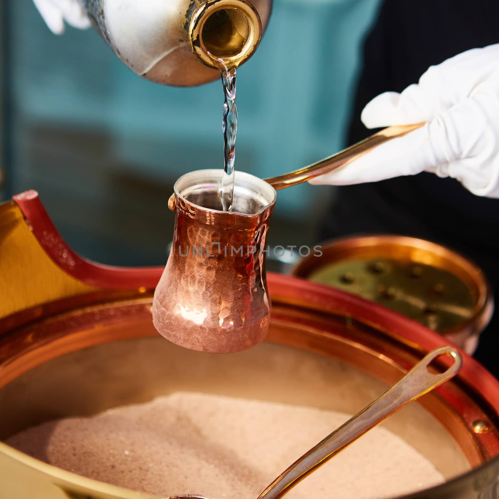 Preparation of Turkish coffee in the cezve in the sand at cafe bar by sarymsakov