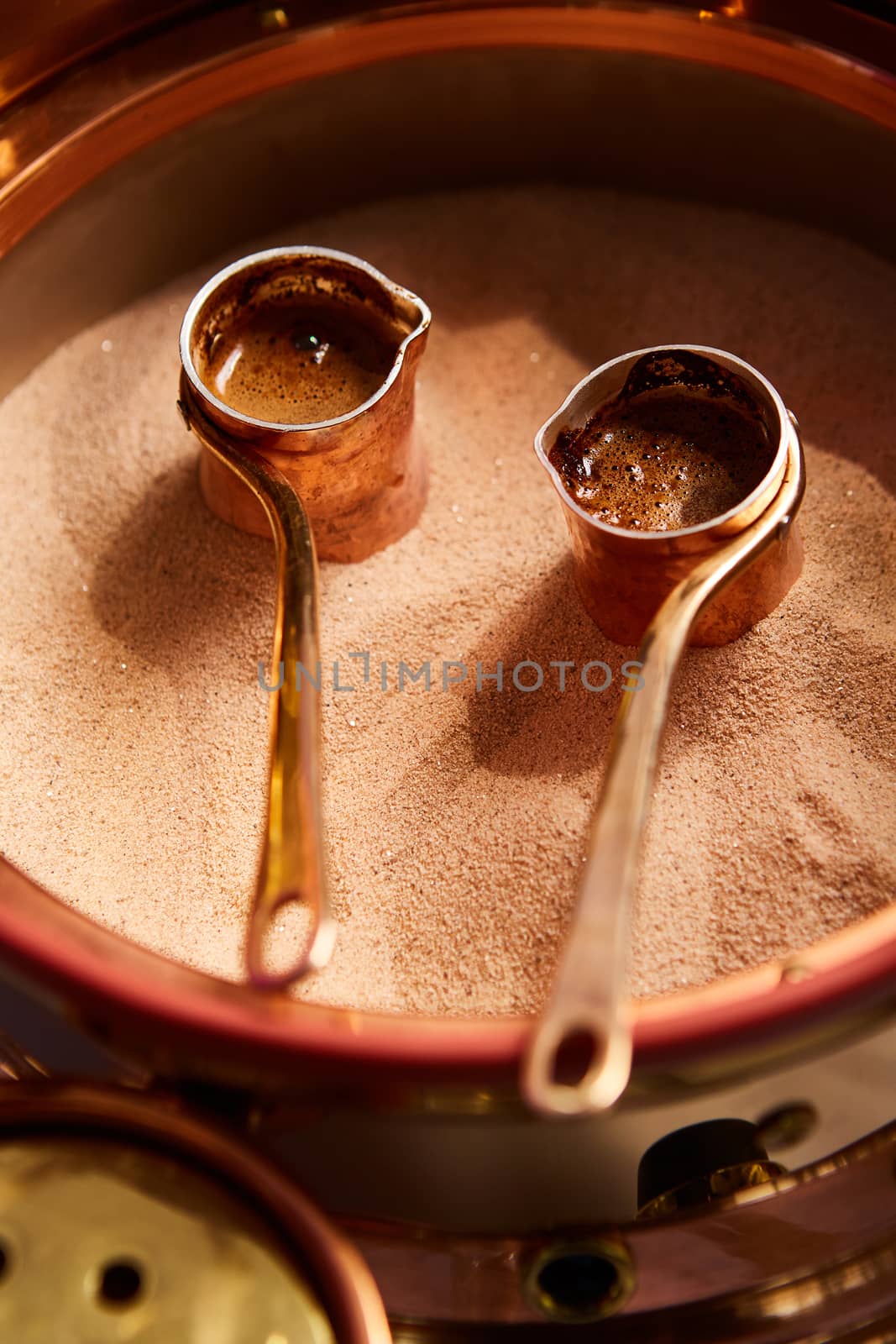 Preparation of Turkish coffee in the cezve in the sand at the cafe bar