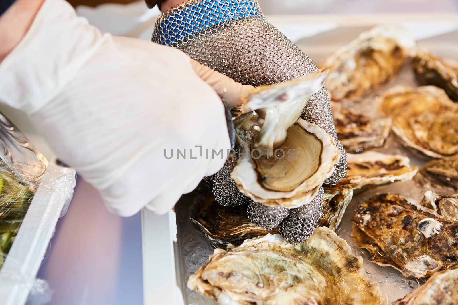 Fresh oyster held open with knife in hand by sarymsakov