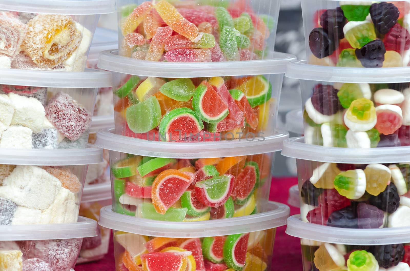 Different candies in plastic containers on a market stall.
