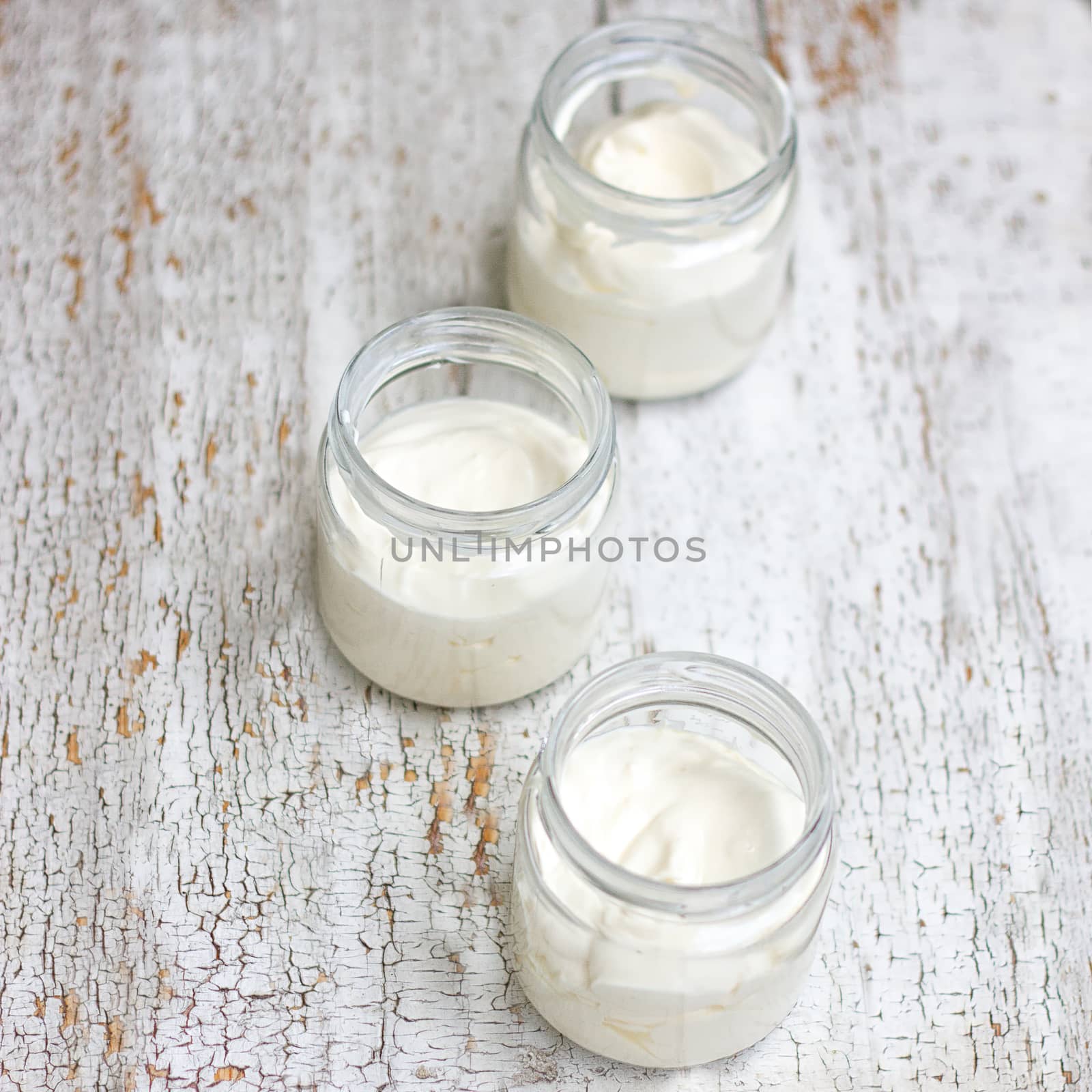 Three glass jars with milk on white wooden background