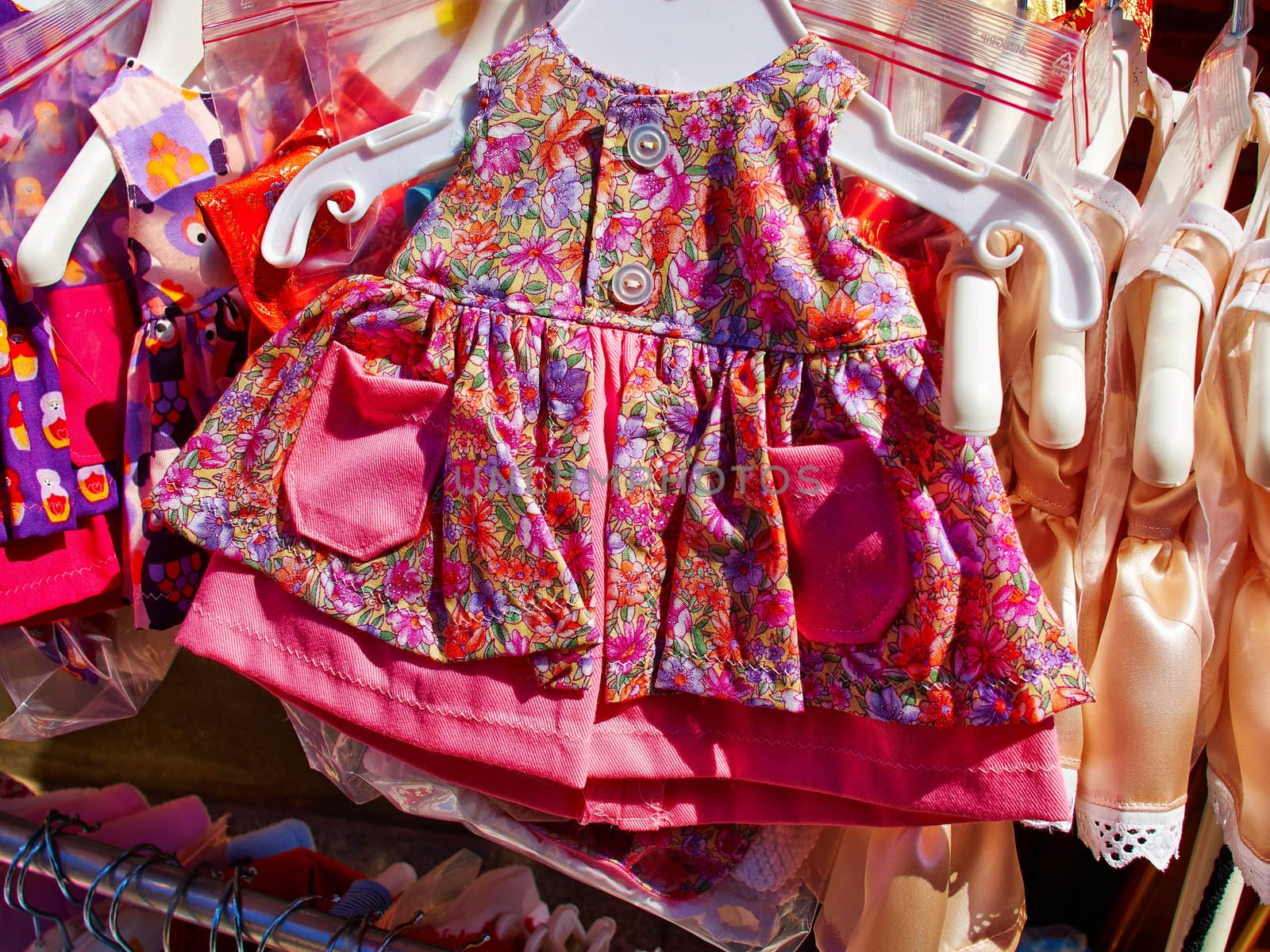 Baby girl beautiful elegant bright summer dresses on hangers in a display shop