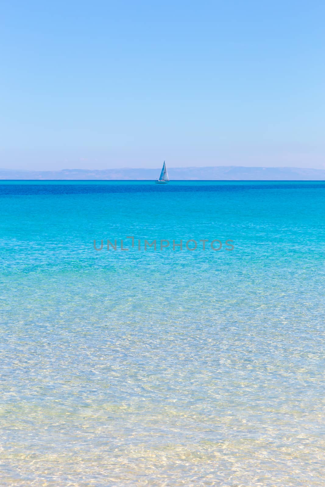 White sail boat at the beautiful turquoise blue mediterranean Pelosa beach near Stintino,Sardinia, Italy.