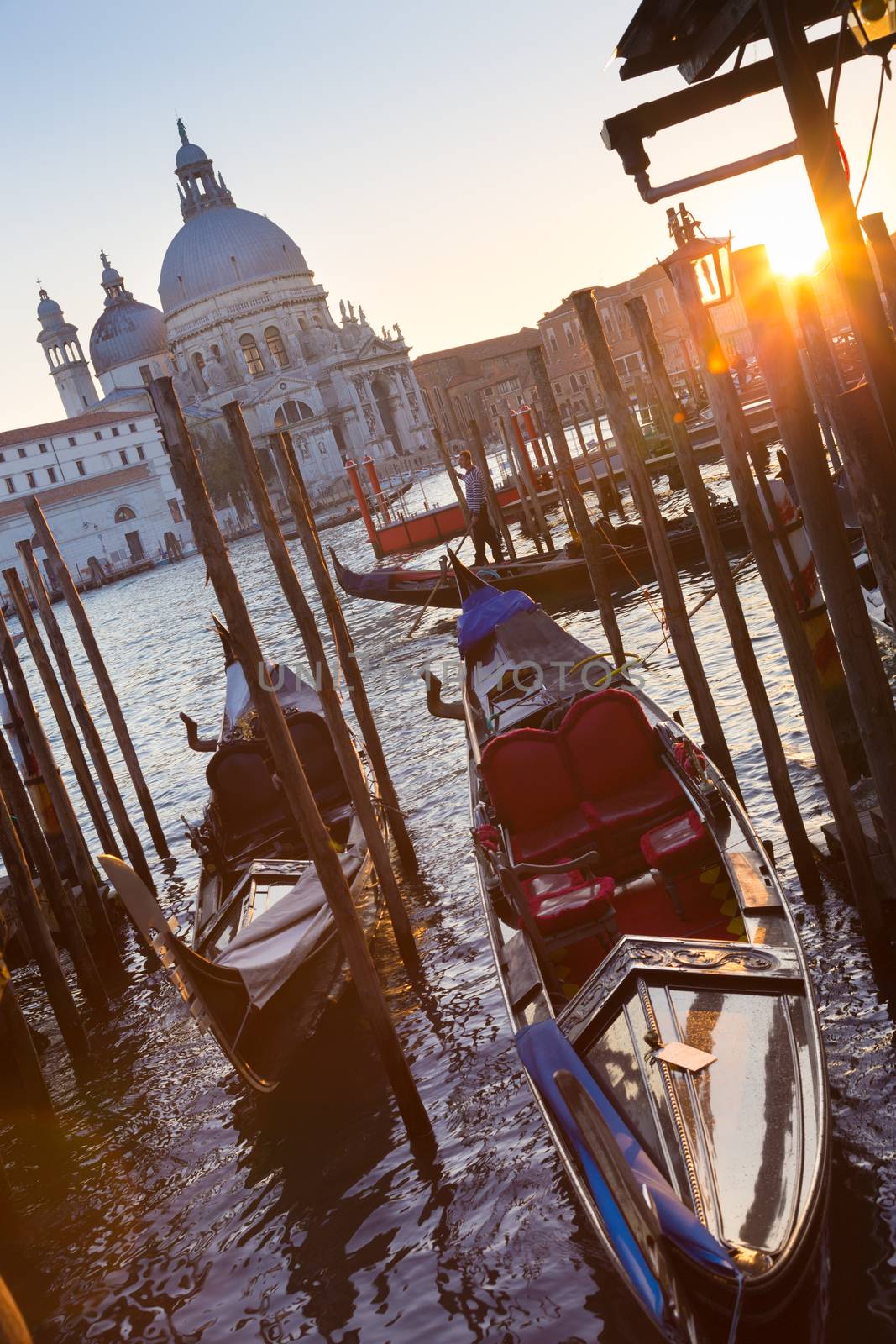 Venice, Italy - October 31, 2014: Traditional wooden boads and a gondolier in the Grand Canal in front of Santa Maria della Salute in sunset.