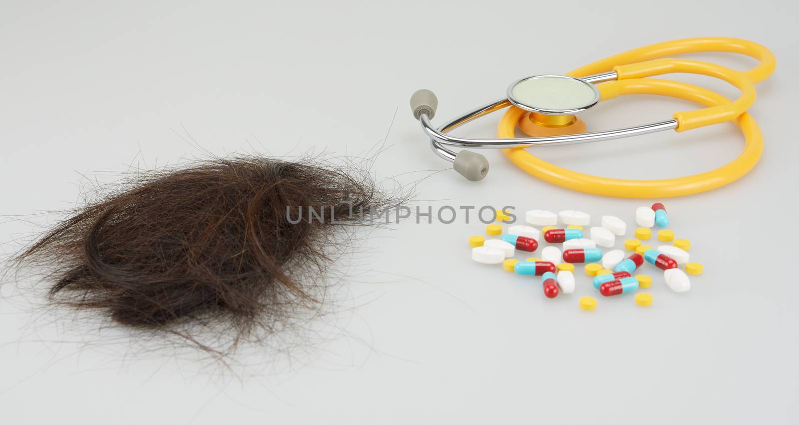 Brown lost hair with medicine and stethoscope on white background.