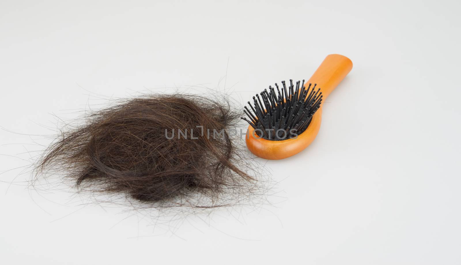 Wooden hair brush with lost brown hair on white background.