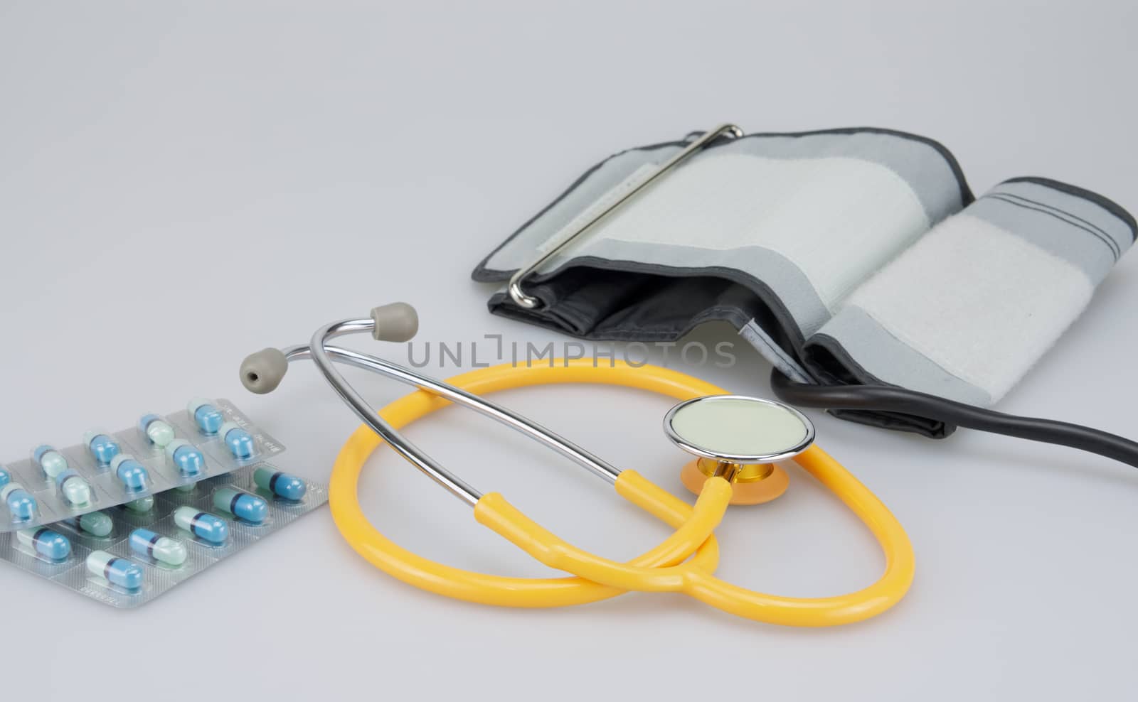 Pack of medicine with blood pressure equipment placed on white background.