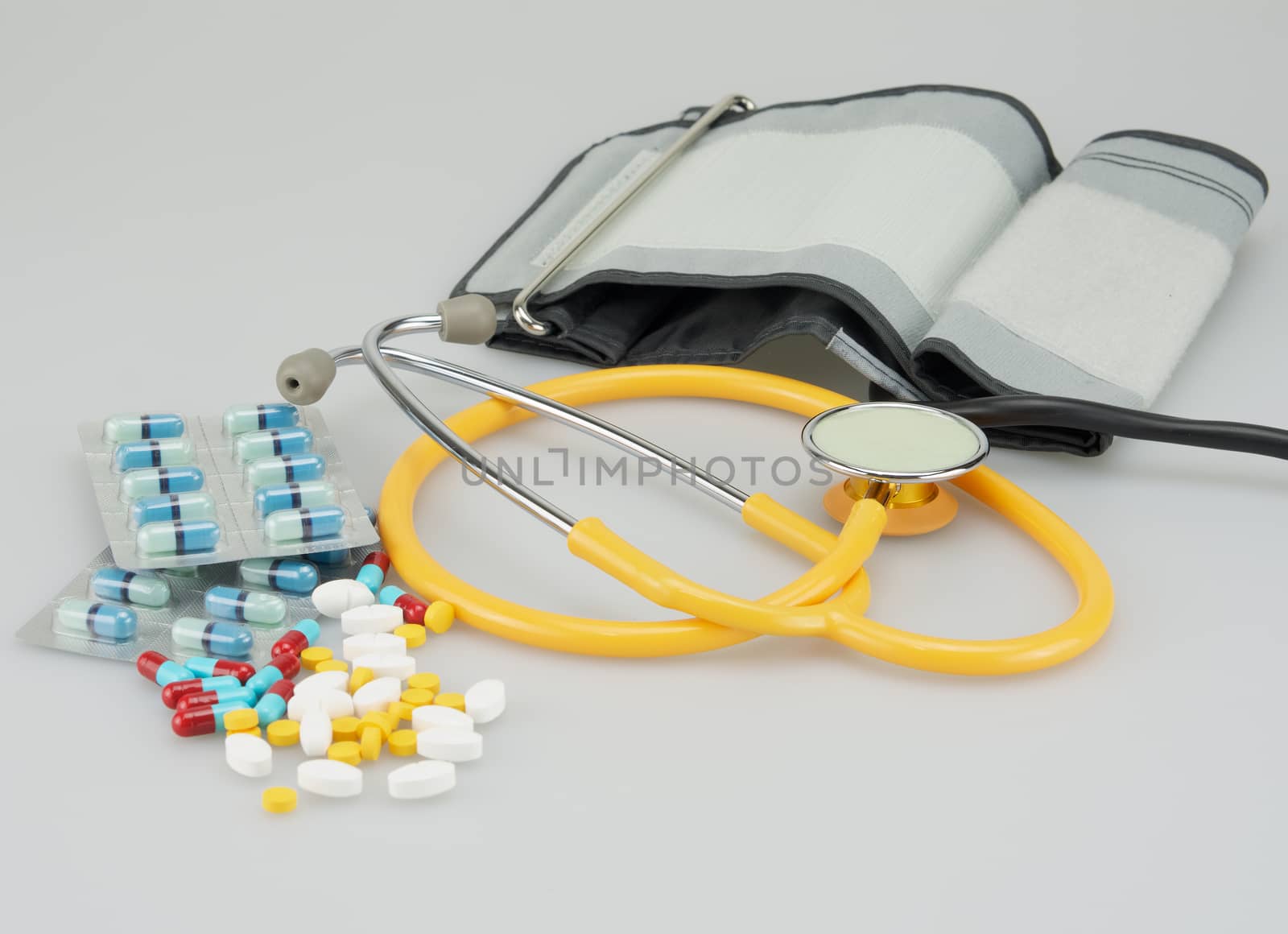 Lot of medicine with blood pressure equipment placed on white background.