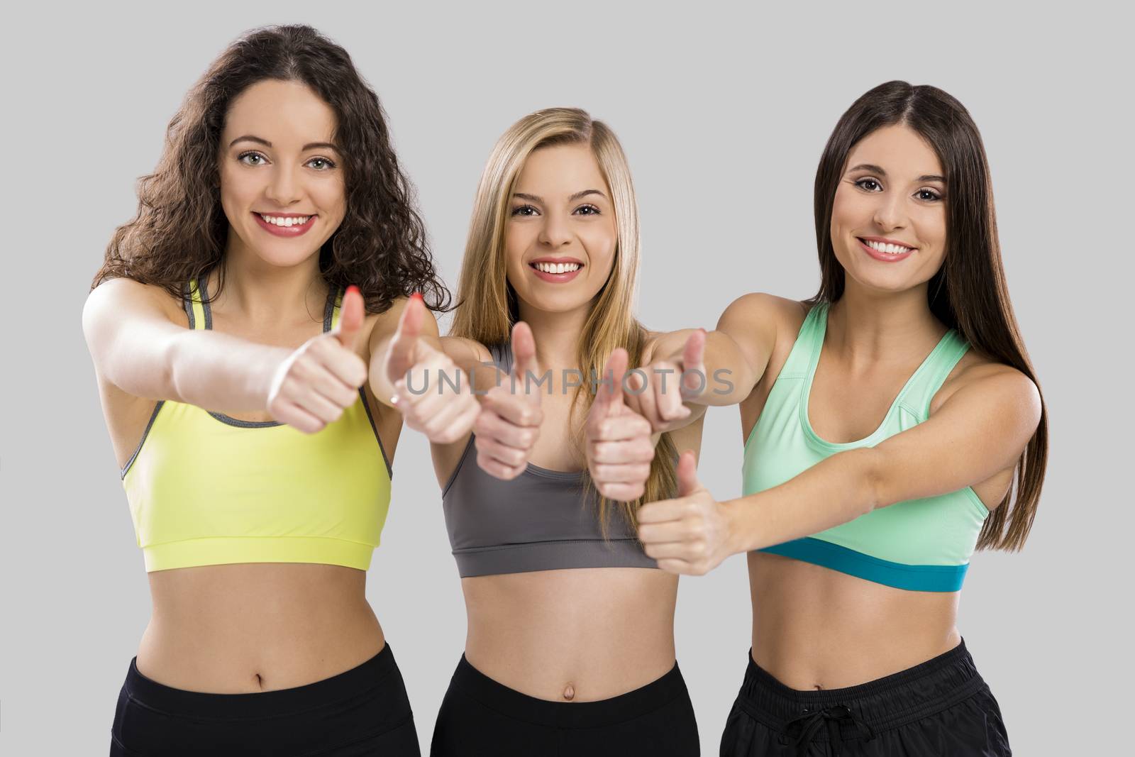 Portrait of three beautiful and athletic girls with thumbs up