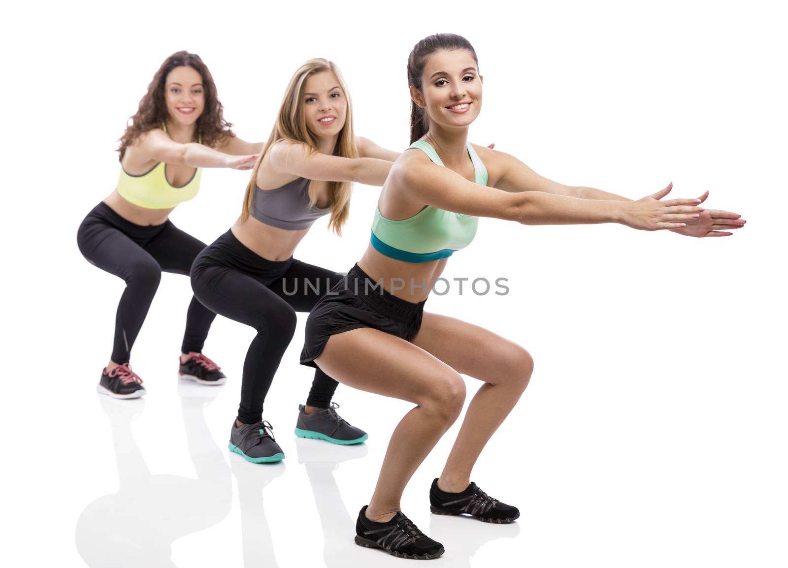 Portrait of three beautiful athletic girls making group exercises