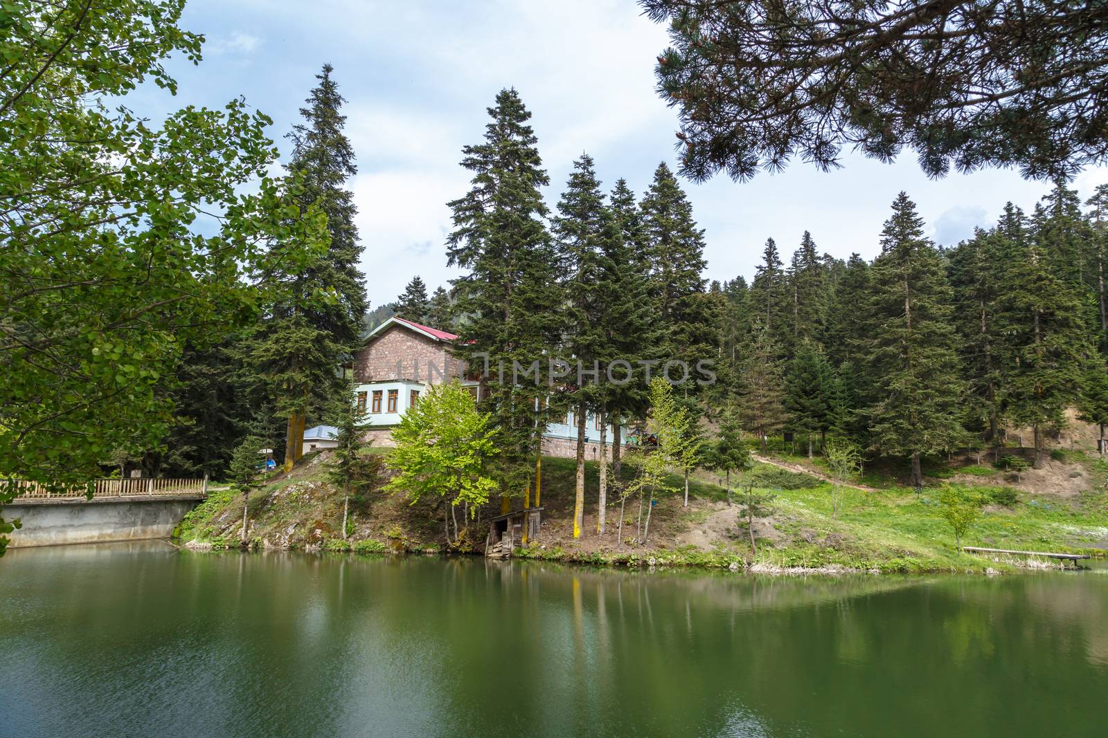 View of small Akgol lake in Ayancik, Sinop around big mountains with high pine trees on cloudy sky background.