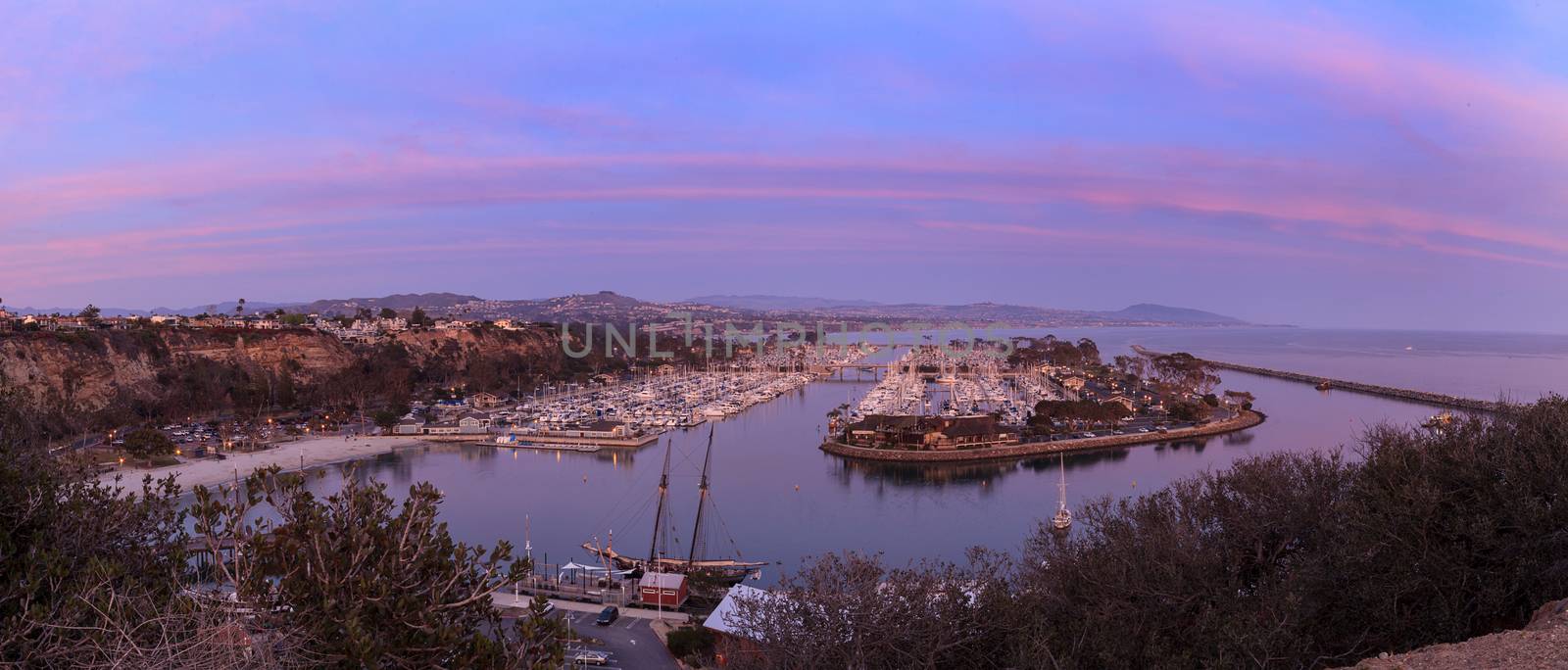 Panoramic Dana Point harbor view of the sunset and a private beach below