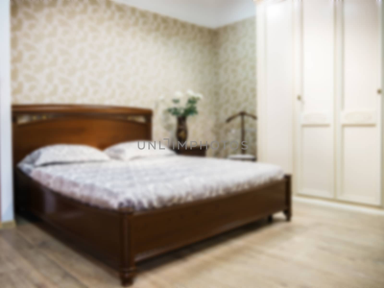 Blurred bedroom with brown wooden bed by fascinadora