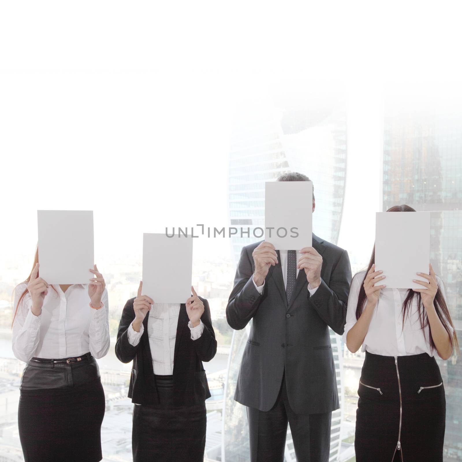 Portrait of business people group holding white papers and covering their faces