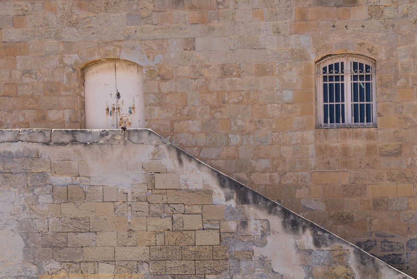 Old building made of stone bricks with a window and a gate. Line of the staircase. Capital of island Malta, Valletta.