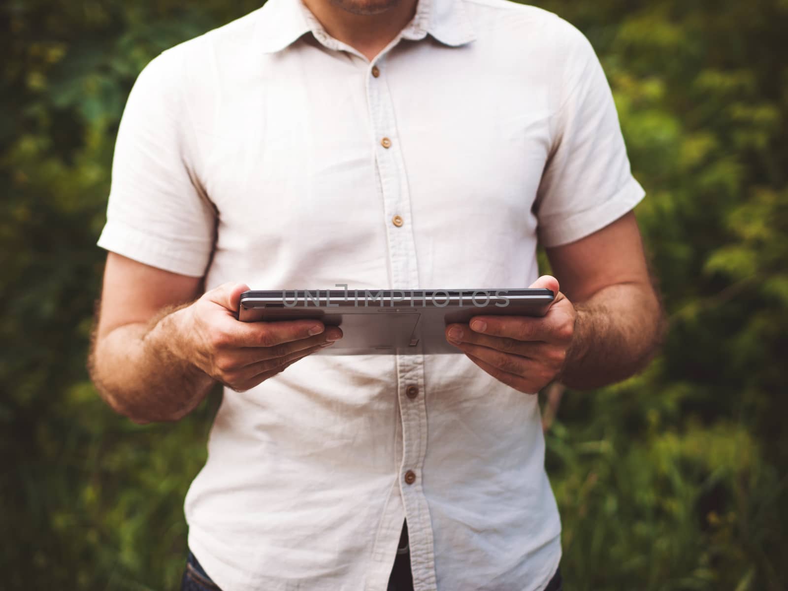 Man reading digital tablet outdoors, close up by fascinadora