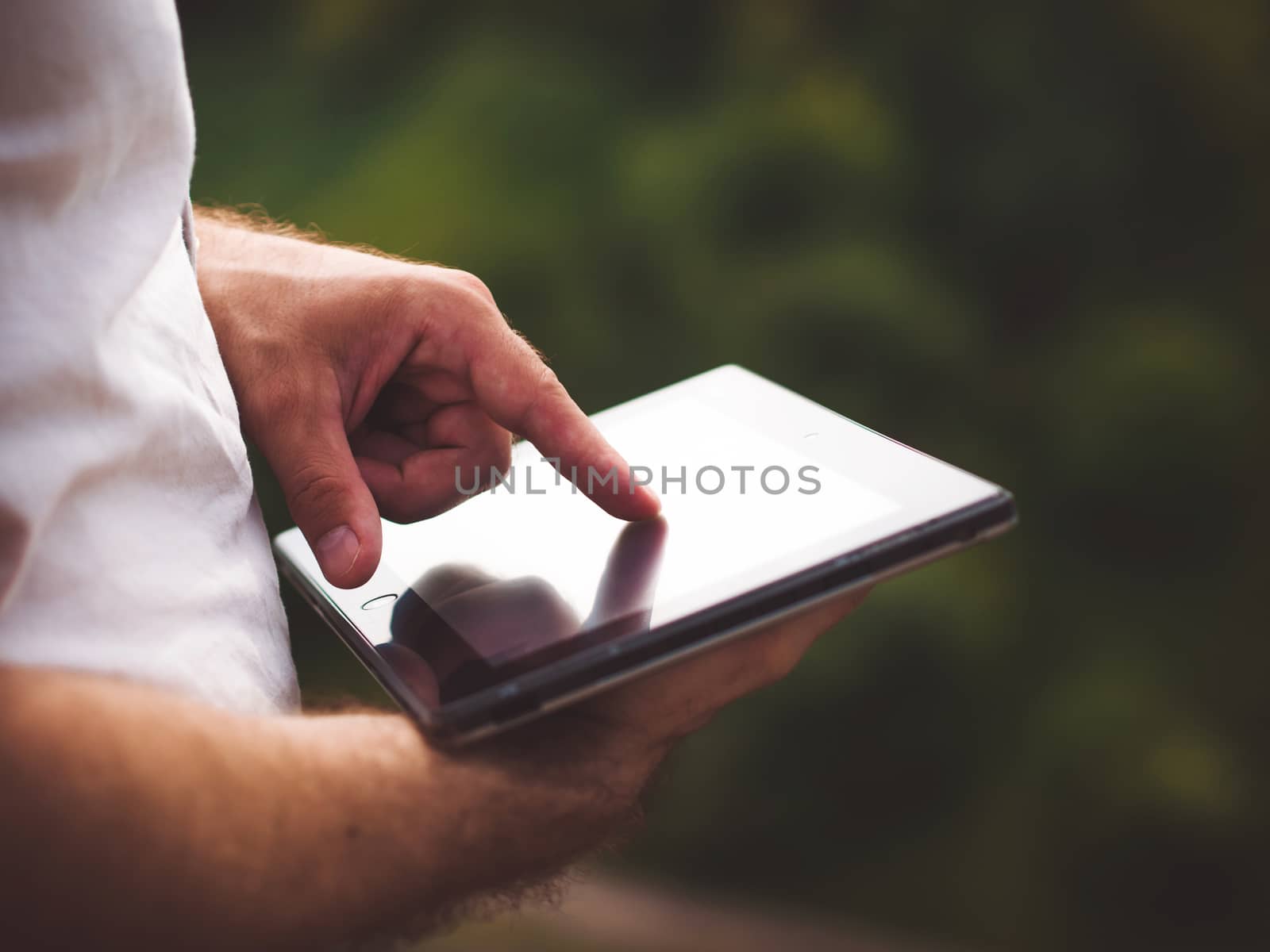 Smart casual man with digital tablet outdoors, close up. Focus on finger. Modern remote work concept.