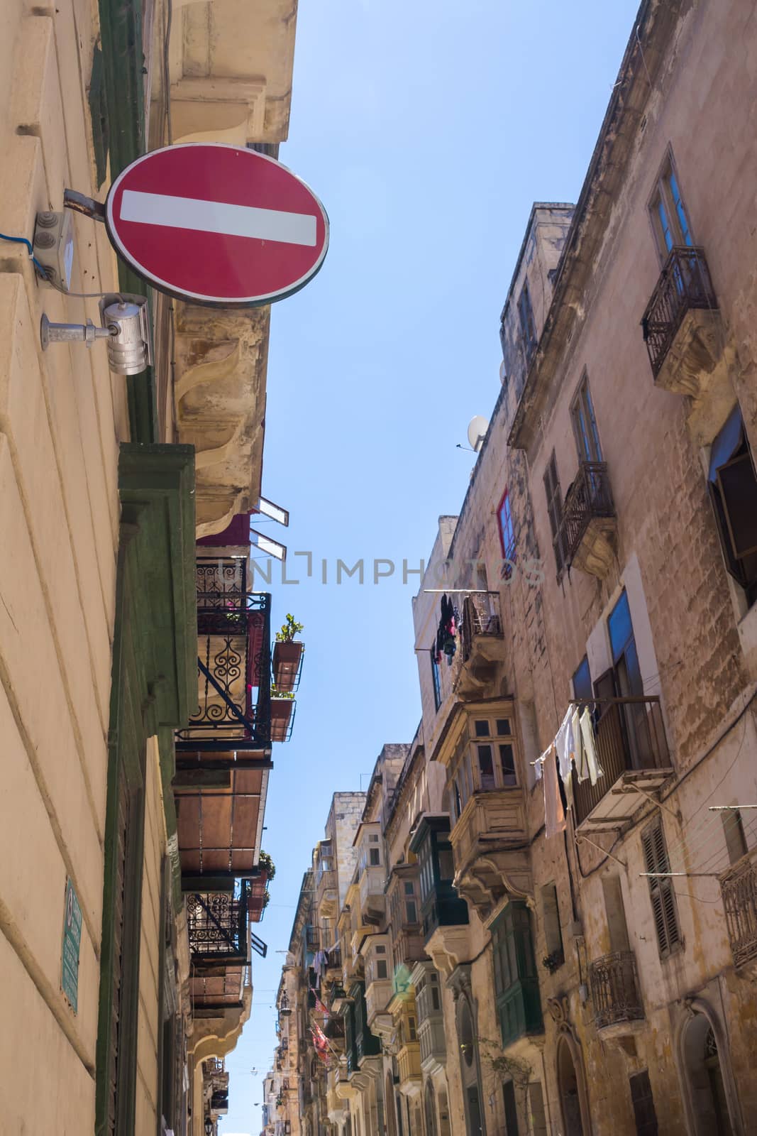 One of many narrow streets in the capital of island Malta - Valletta. View on the windows and balconies. No entry sign in the foreground.