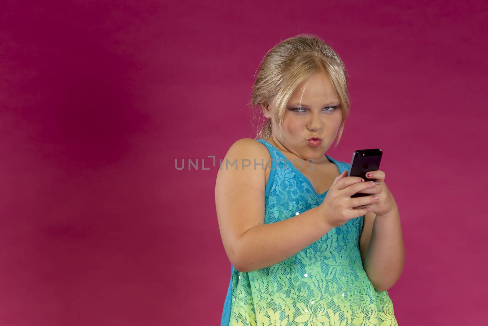 A young child posing in a studio environment with an electronic device.