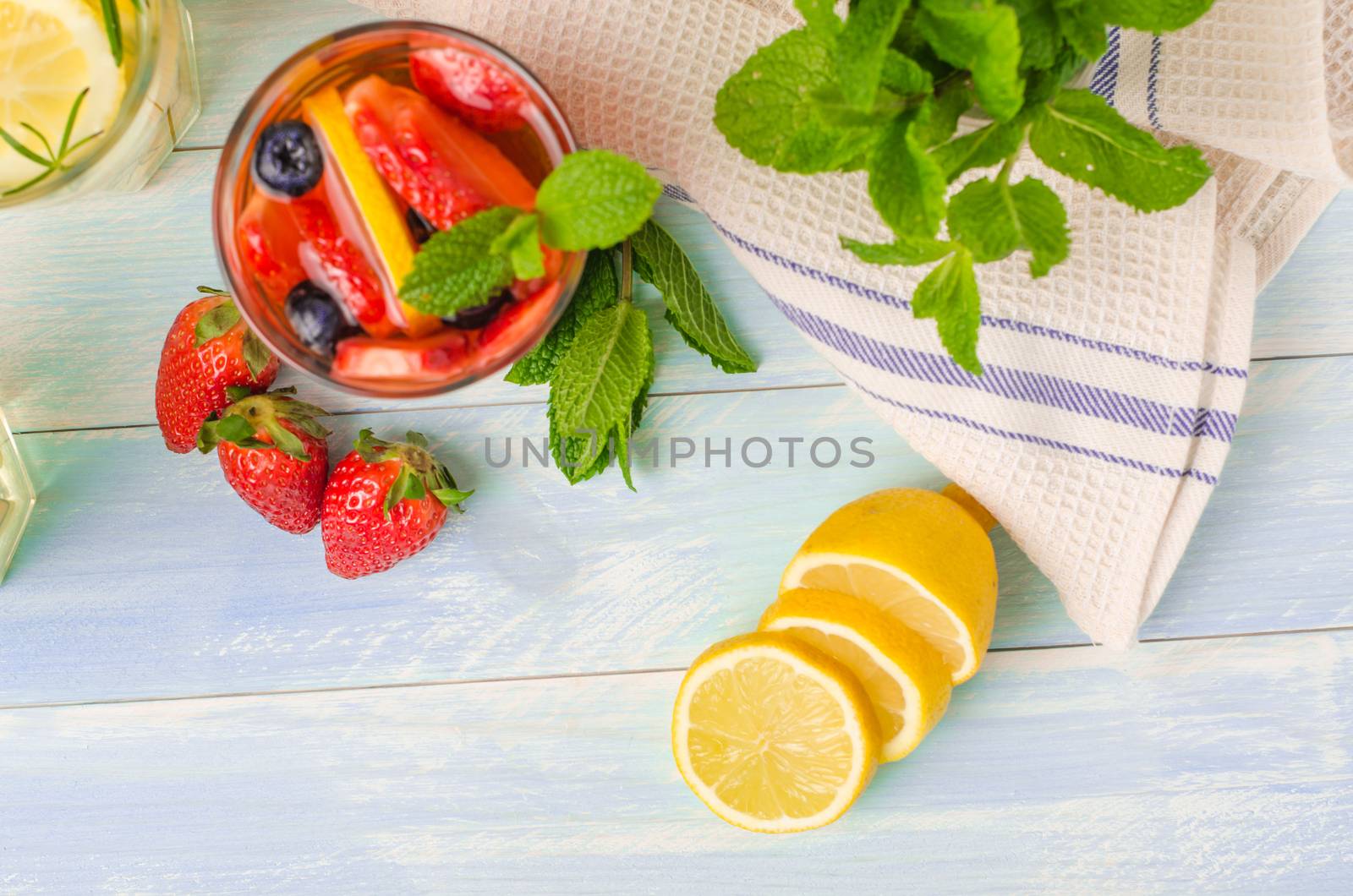 Detox fruit infused flavored water. Refreshing summer homemade cocktail with lemon, orange, strawberries and blueberries