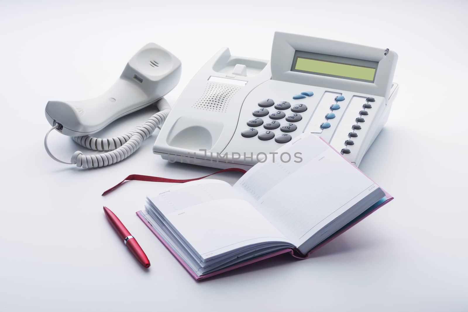 The telephone set of milk white color, notepad and pen on a white background