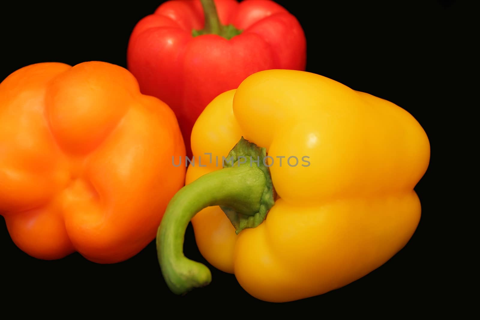 Photo of red and yellow raw pepper on black background