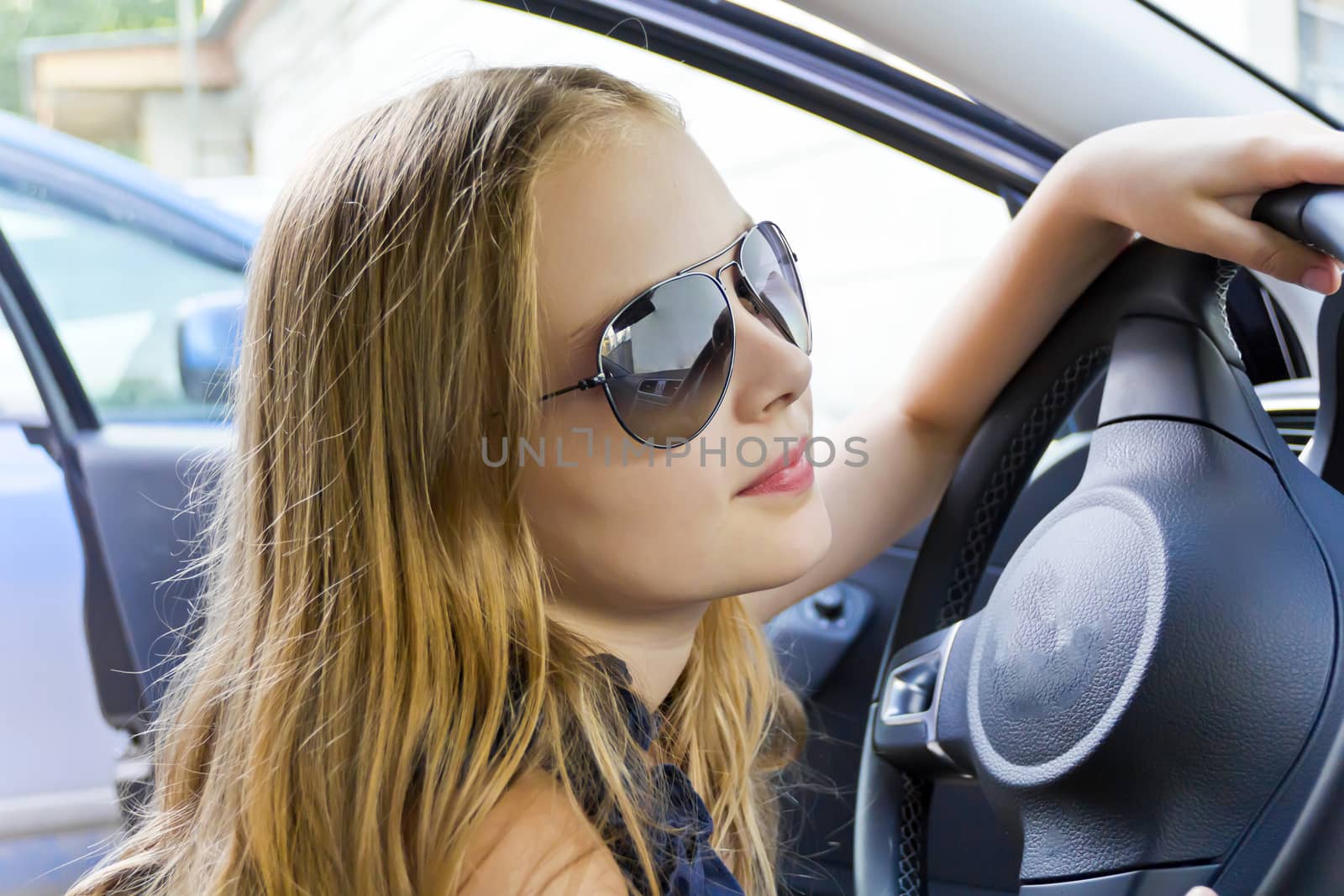 Cute girl with blond hair inside car in sunglass
