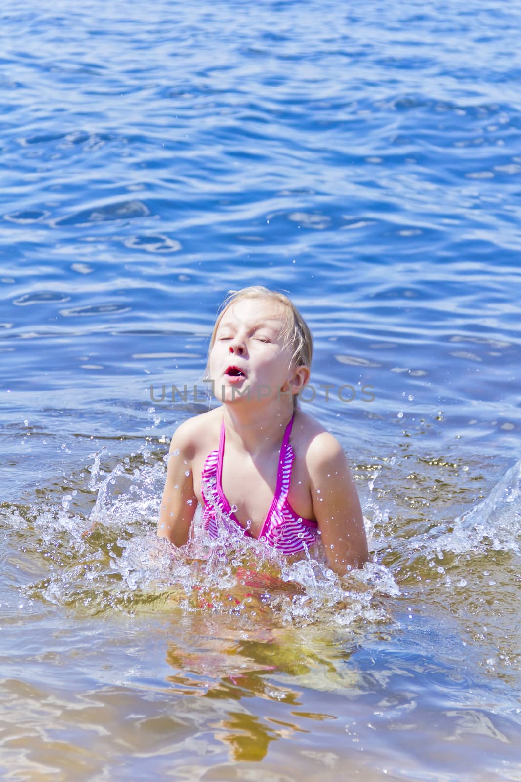 Jumping girl in pink swimsuit with droplets of water