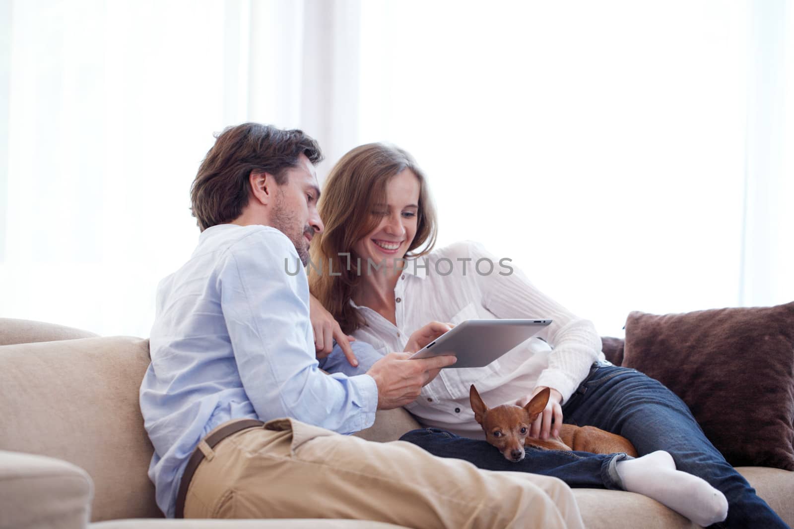 Cheerful couple using digital tablet at home