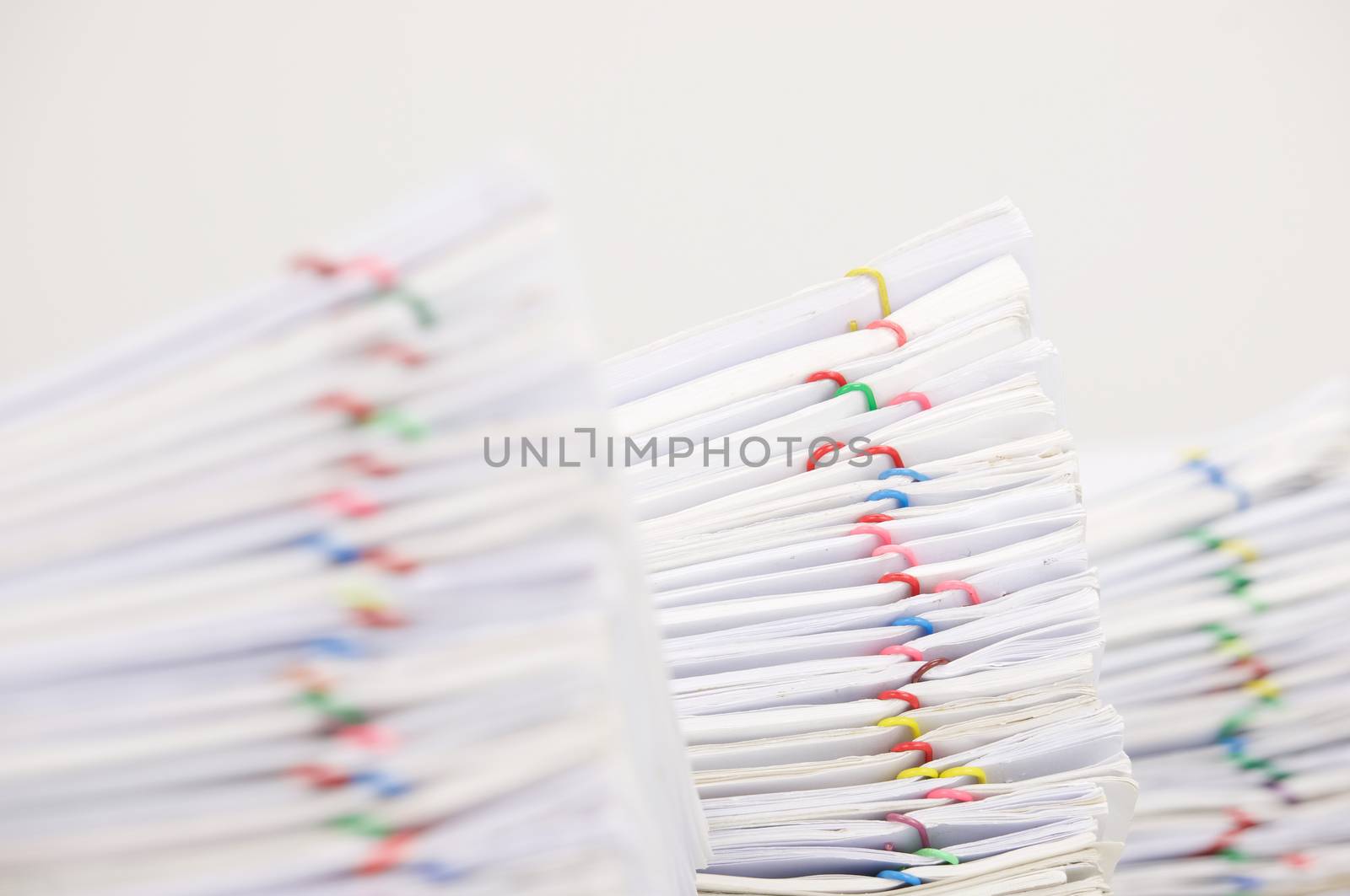 Pile overload document of report with colorful paperclip have blur pile overload paperwork as foreground and background with white background.