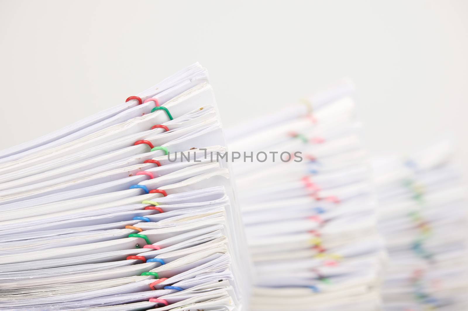 Pile overload document of report with colorful paperclip have blur pile overload paperwork as background with white background.