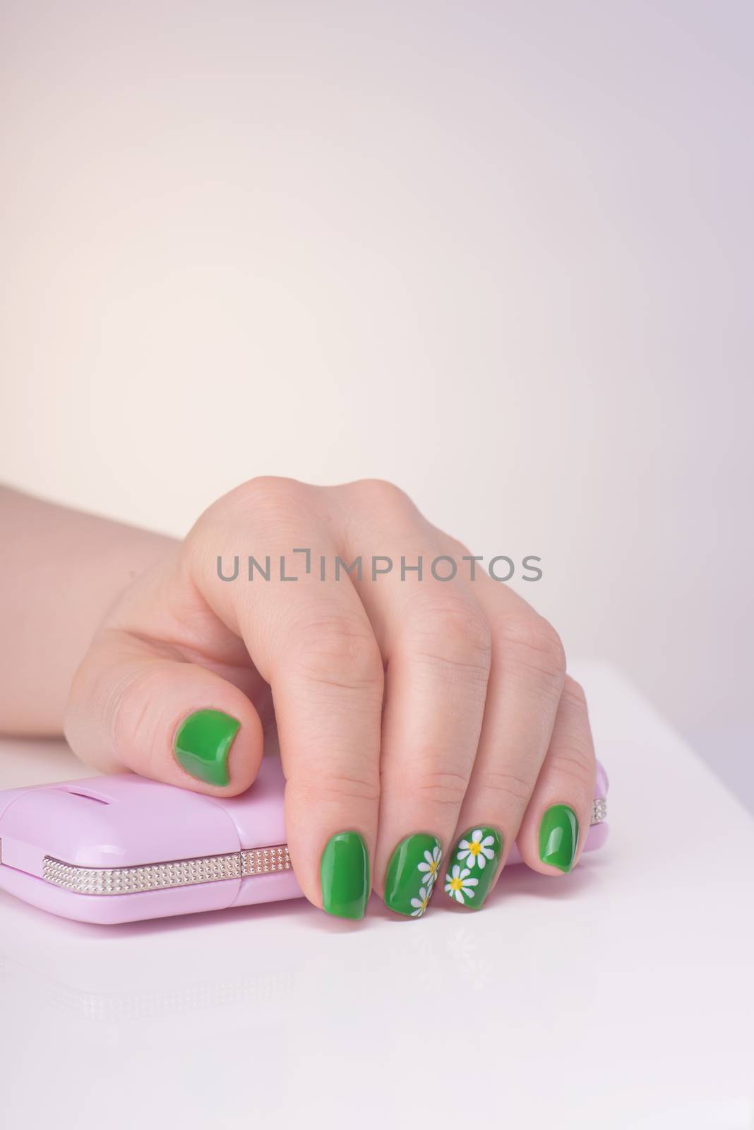 Female left hand with green manicure on a white table