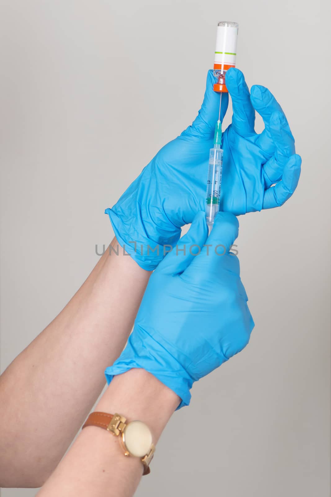 Hands in rubber gloves gather medicine in the syringe from a bottle