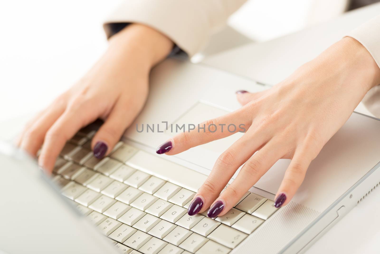 Close-up of female hand with painted nails on the keyboard of the laptop.