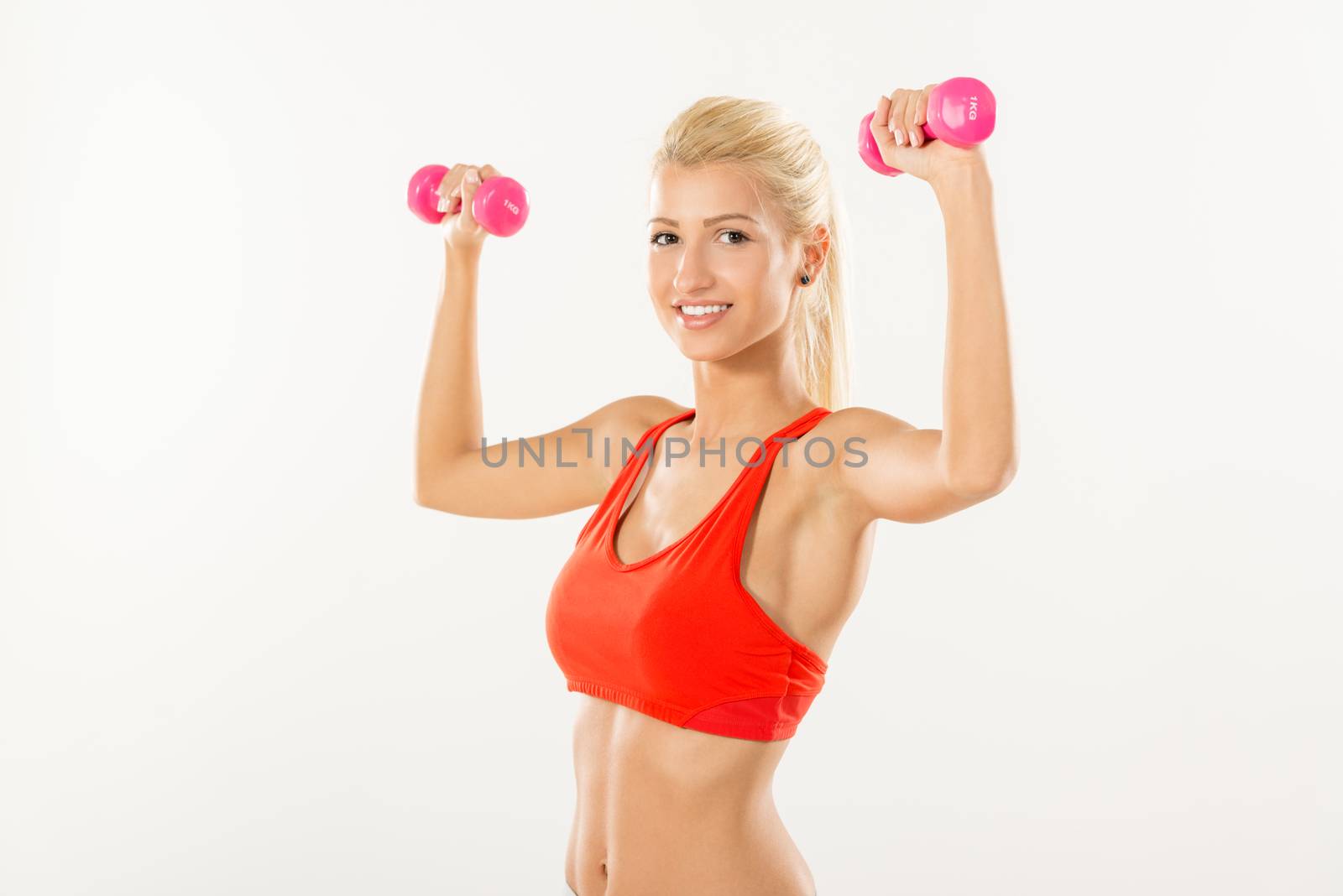 Cute sporty Young girl exercising with dumbbells. Looking at camera.