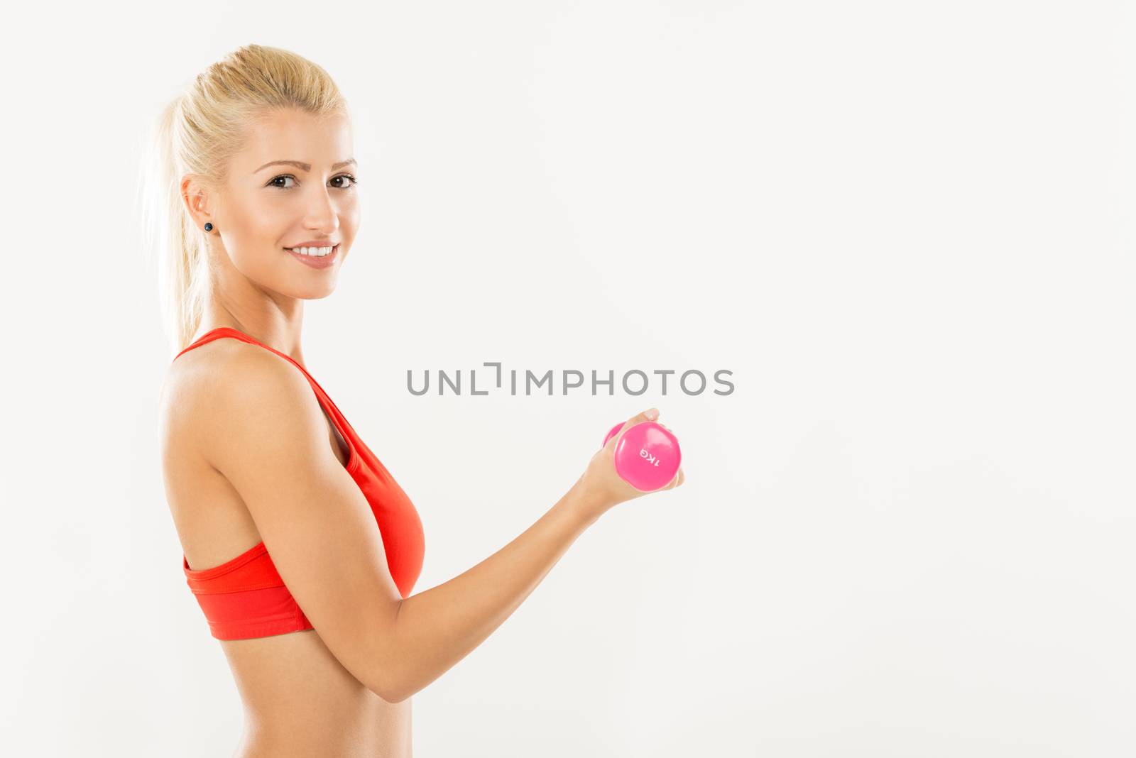 Cute sporty Young girl exercising with dumbbells. Looking at camera.