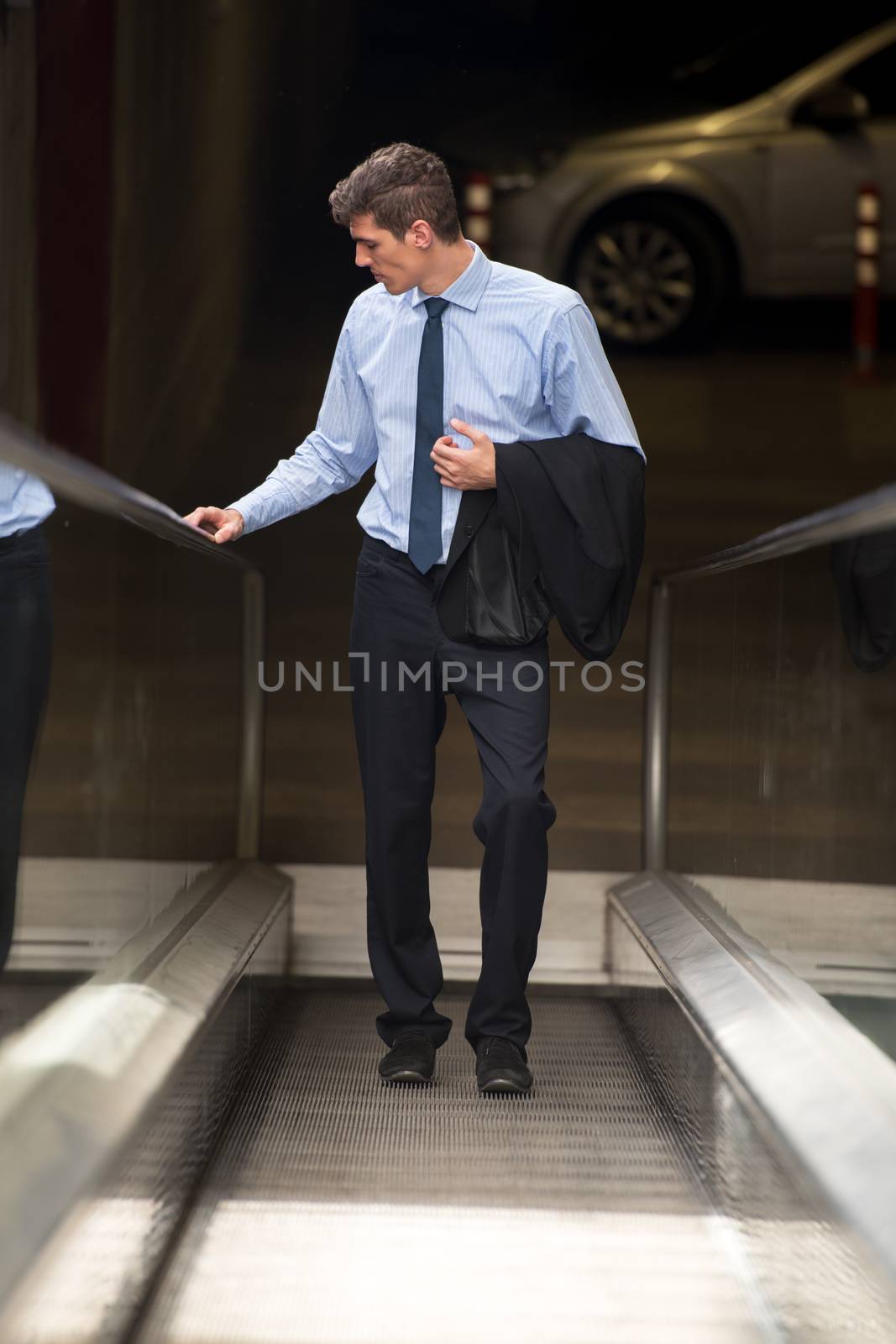 Handsome young businessman on an escalator out of the garage office building, thinking about the work that should be done.