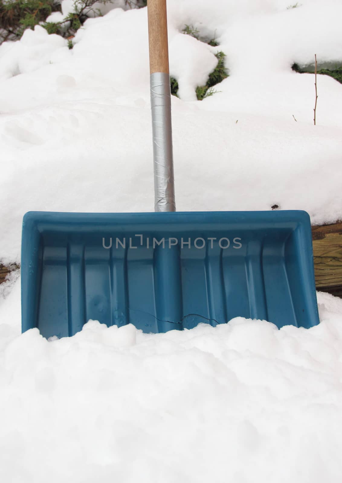 Worn snow shovel repaired with tape around handle