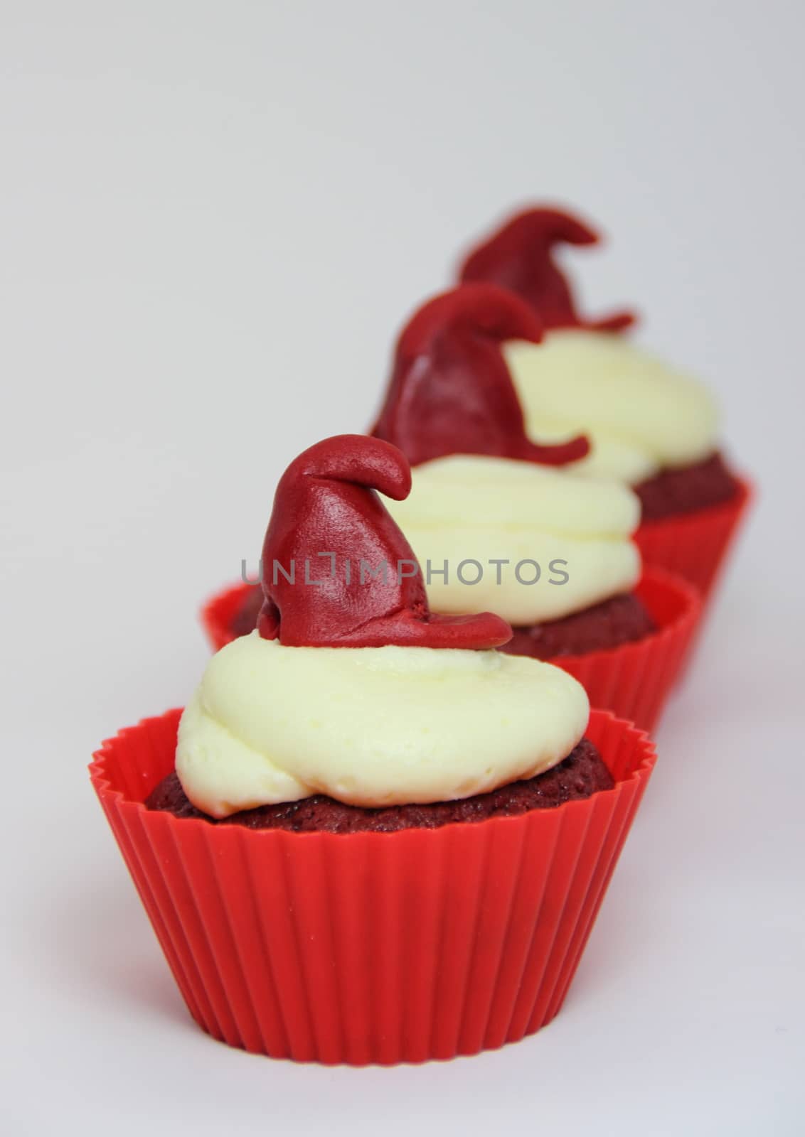 Isolated row of red velvet cupcakes with cream cheese frosting