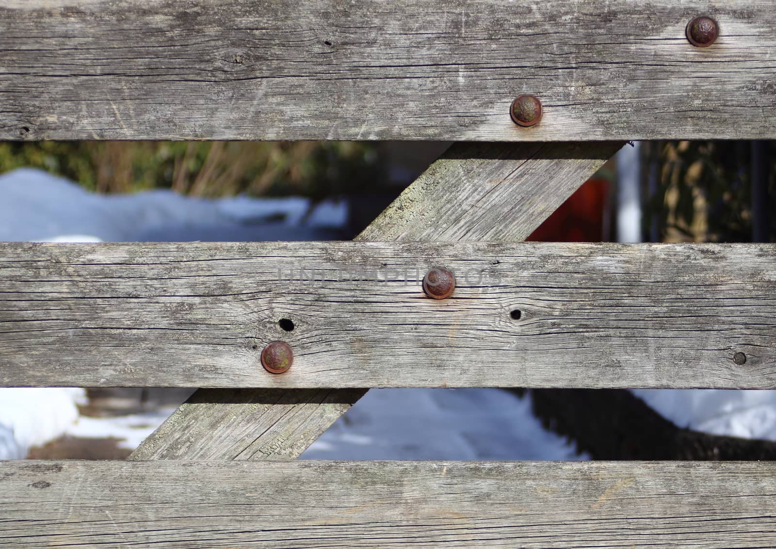 Worn wooden gate with rusty bolts