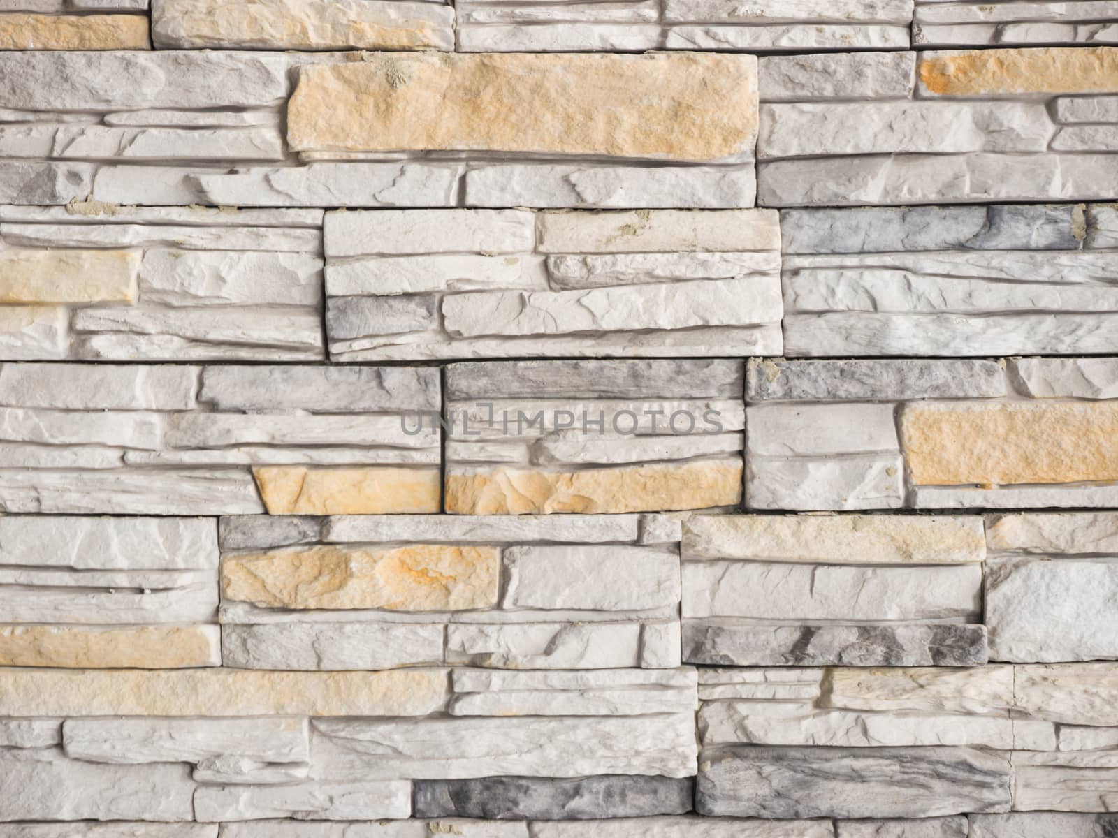 a wall from an artificial gray stone facade with rough fractured surfaces as background