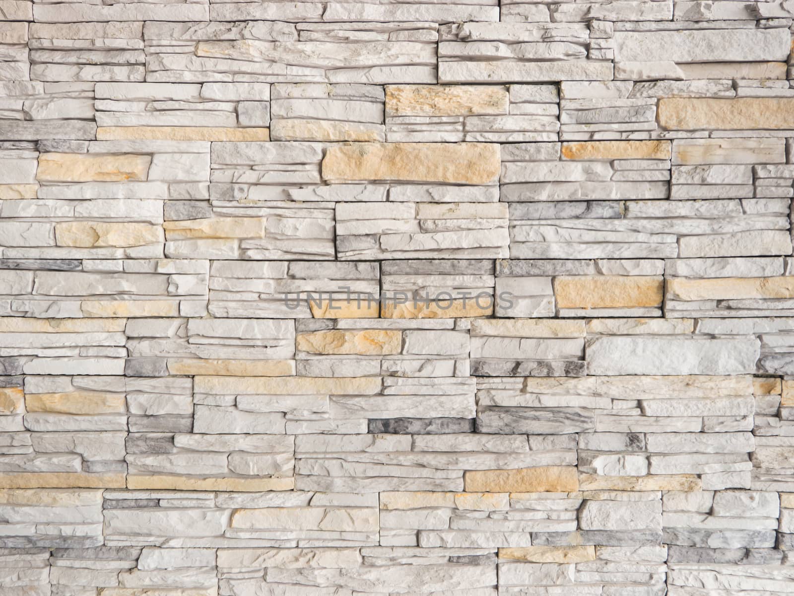 a wall from an artificial gray stone facade with rough fractured surfaces as background