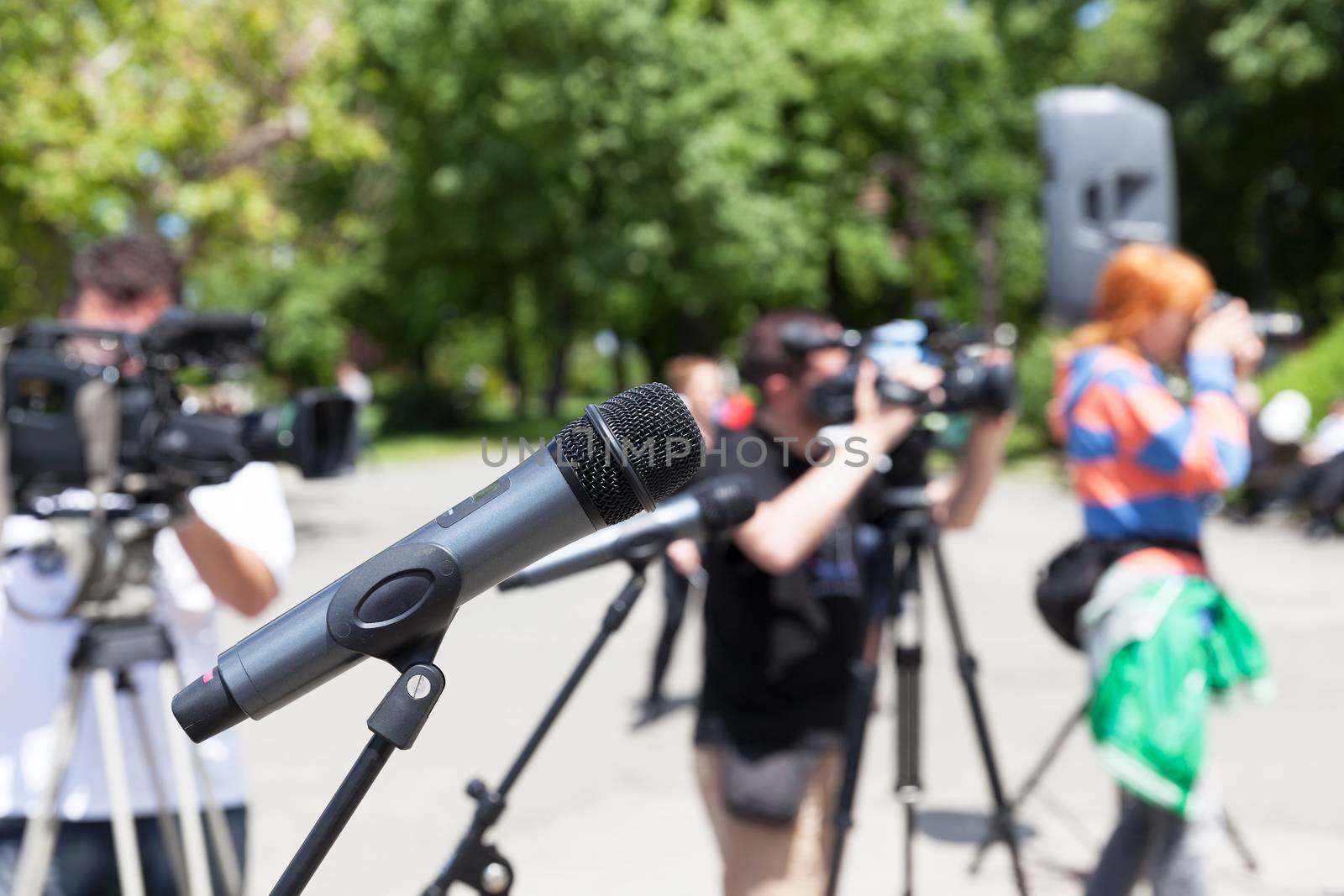 Microphone in focus against blurred camera operators and photographer. Press conference.