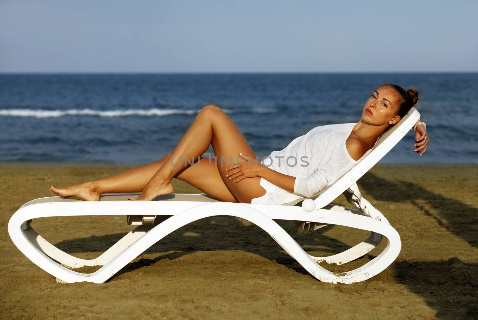 Beautiful girl on a deckchair on the coastline