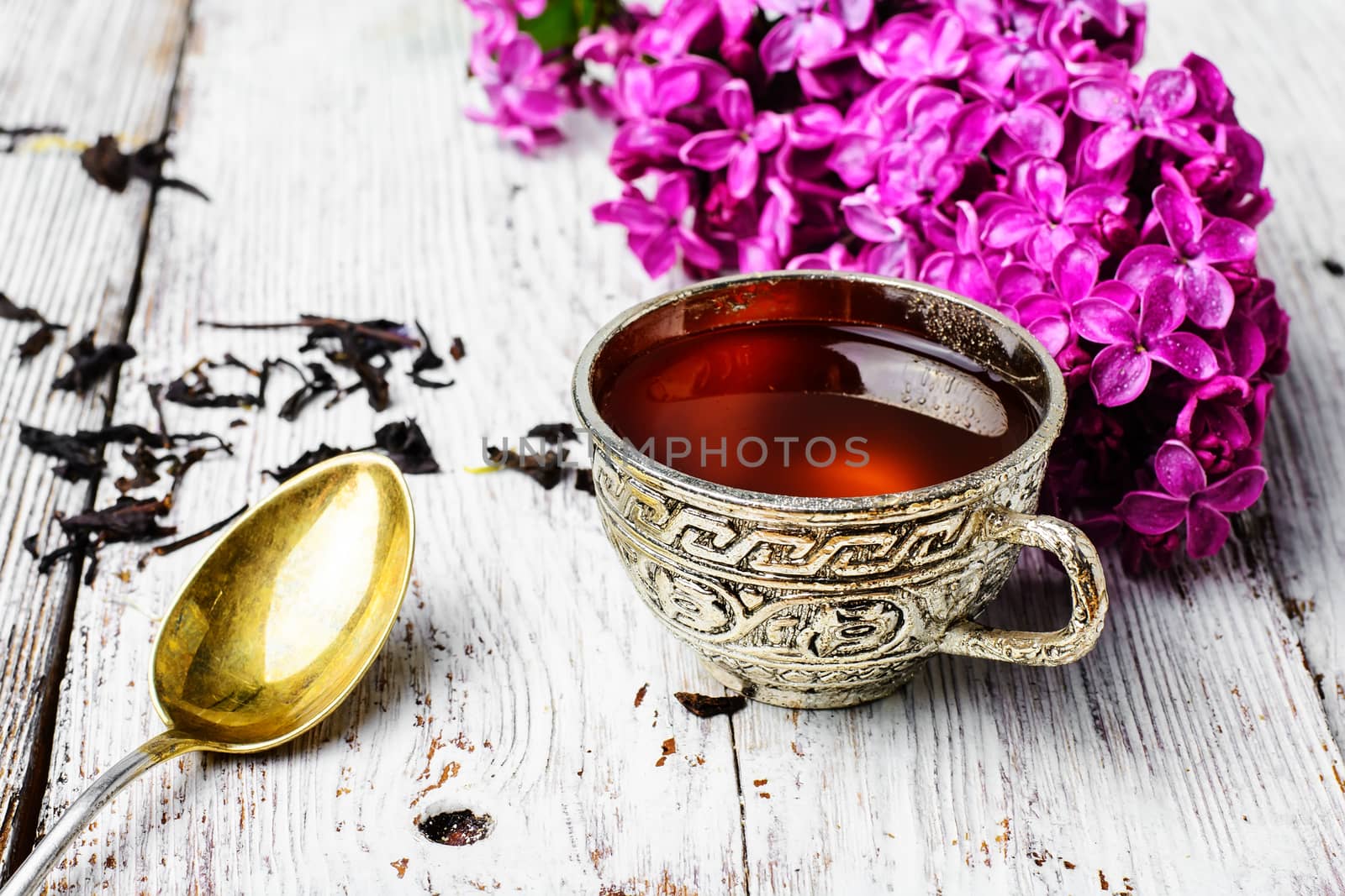 Stylish and fashionable cup of tea and branch of blossoming lilac