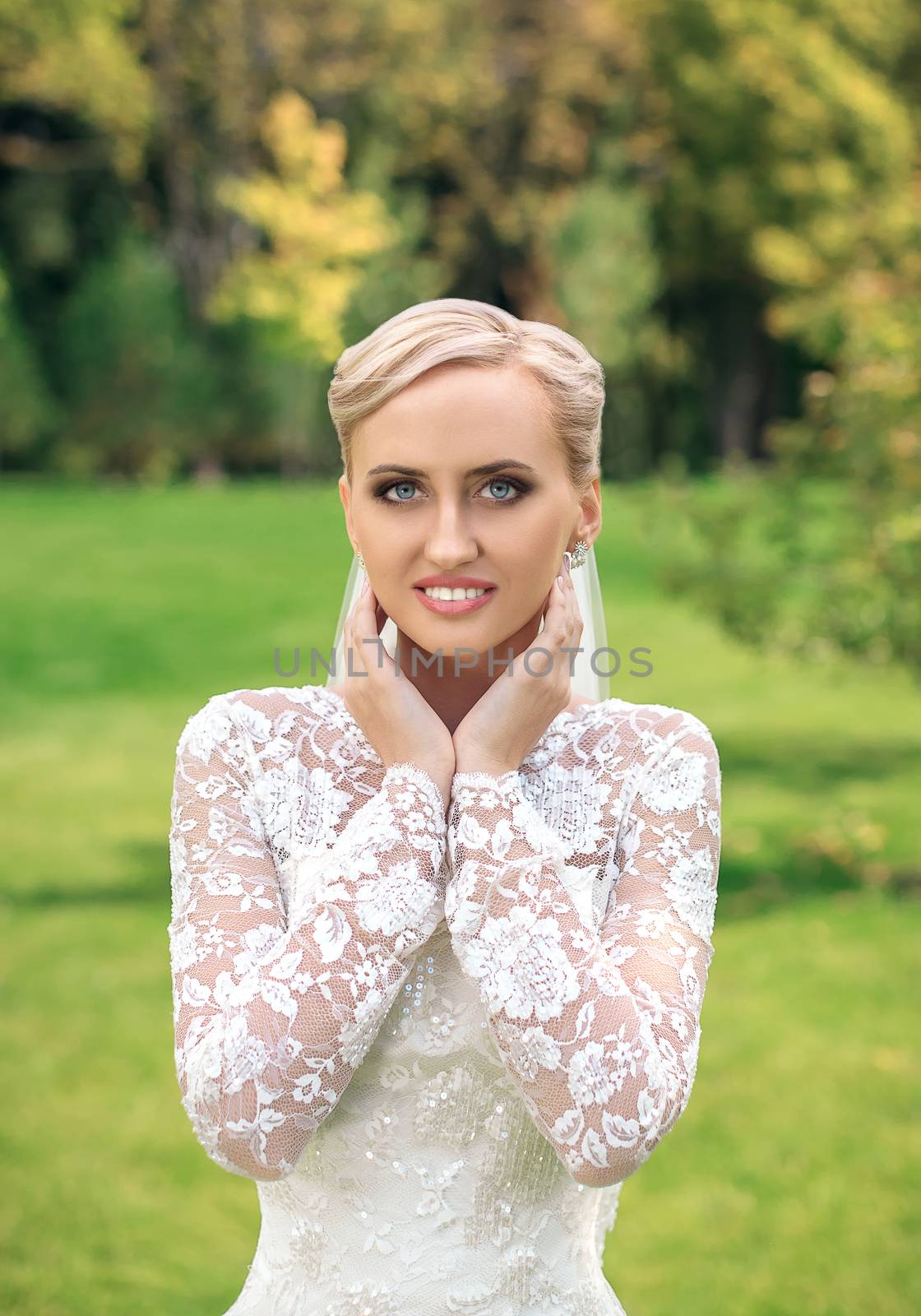 Beauty bride in bridal gown with bouquet and lace veil on the nature. Beautiful model girl in a white wedding dress. Female portrait in the park. Woman with hairstyle. Cute lady outdoors