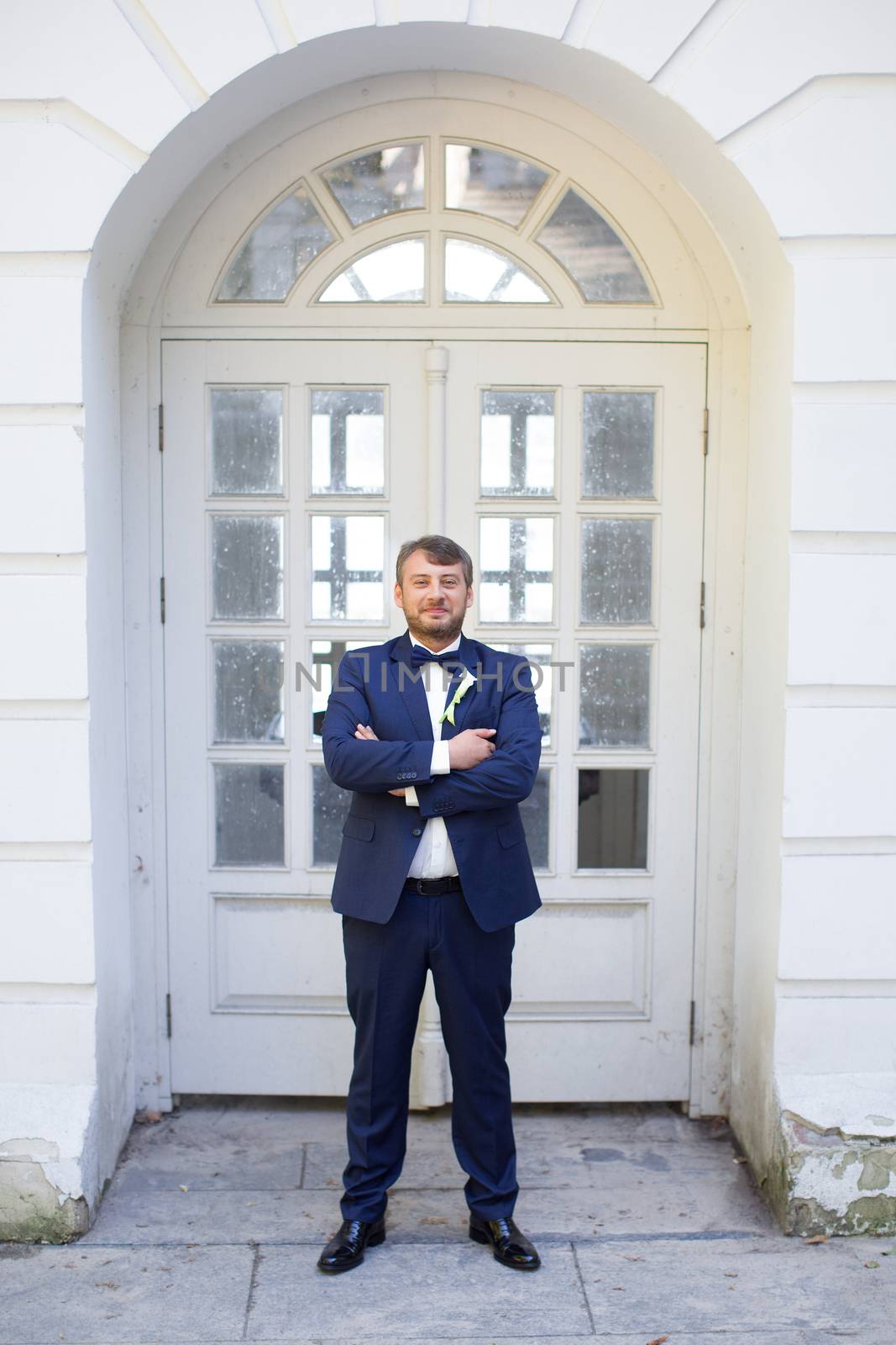 Happy handsome smiling groom in black suit with boutonniere