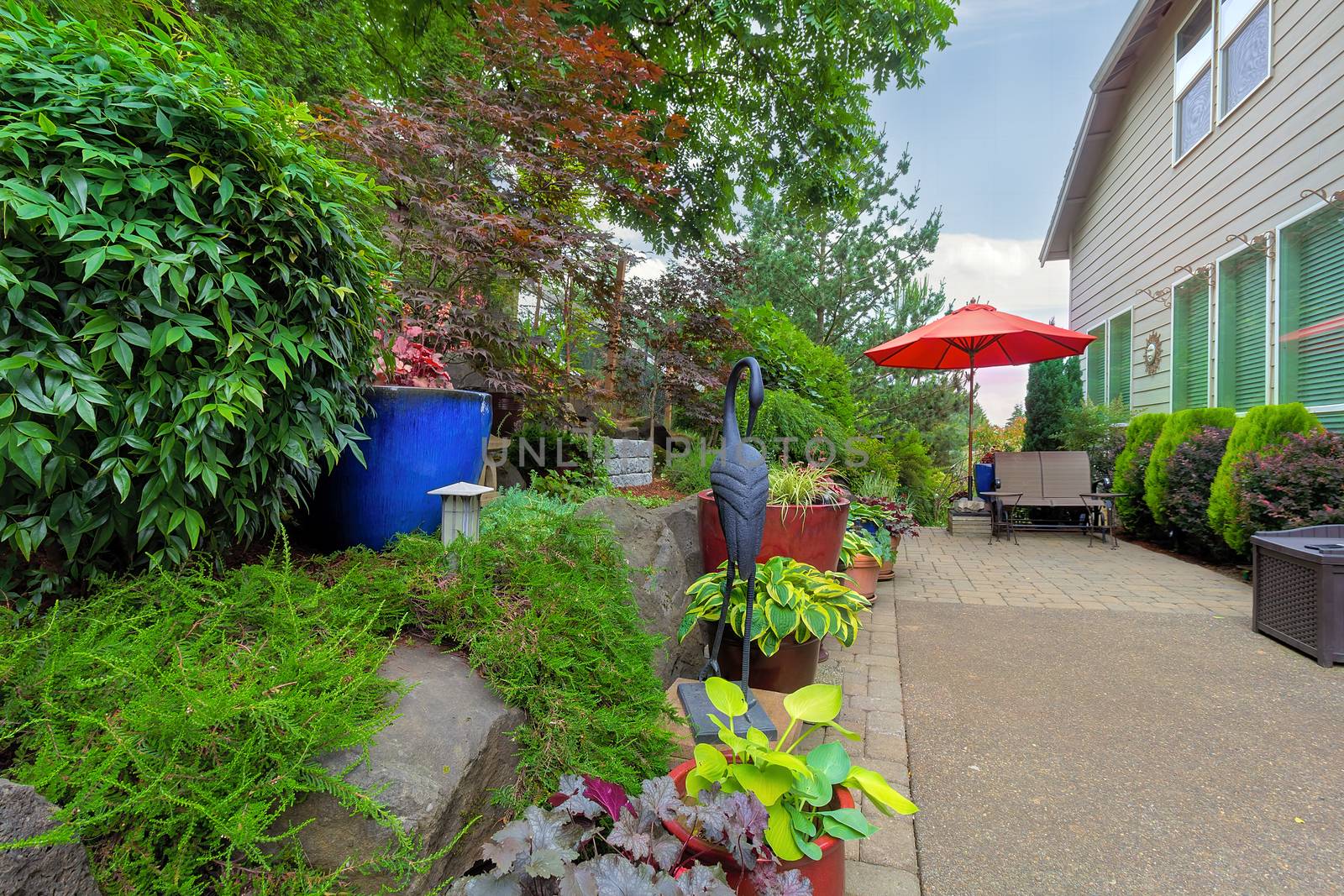 Garden Backyard patio seating red umbrella colorful container pots with plants in landscaping