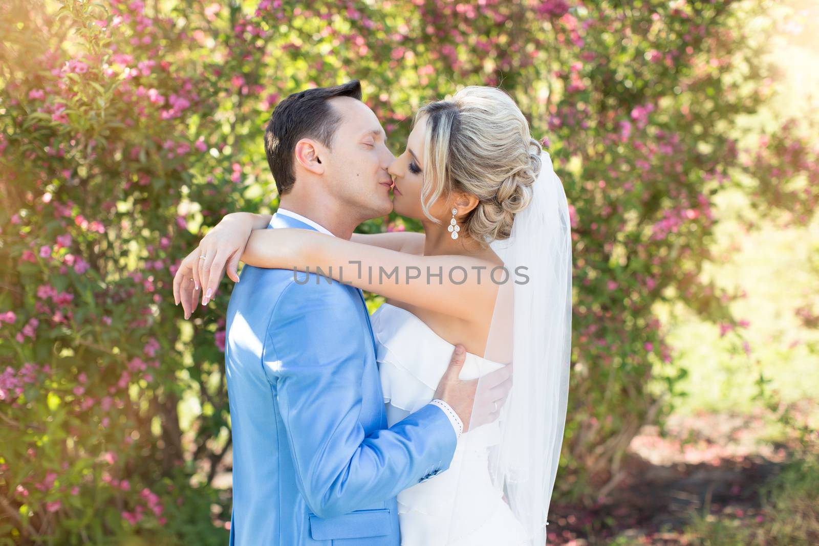 The groom gently kisses the bride on a summer day